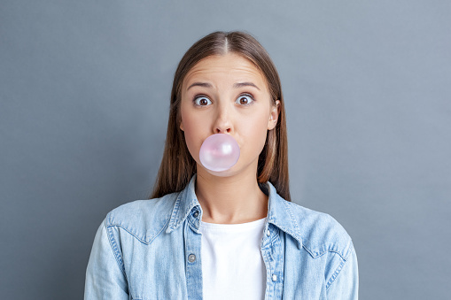 Young woman chewing gum while being surprised.