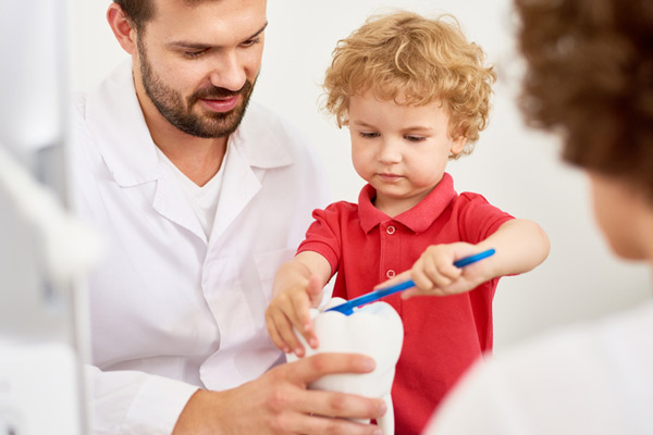 Toddler boy practicing brushing tooth with the dentist at Lakewood Dental Arts in Lakewood, CA