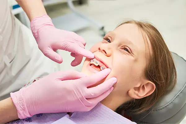 An orthodontist adjusting braces during a maintenance check for a young girl at Lakewood Dental Arts in Lakewood, CA